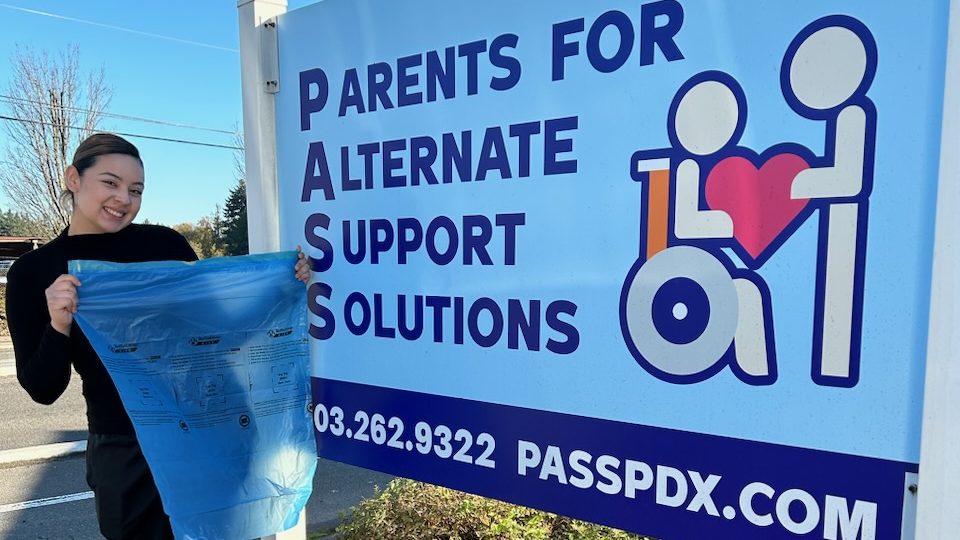 A staff member revealing a new Parents for Alternate Support Solutions business sign.